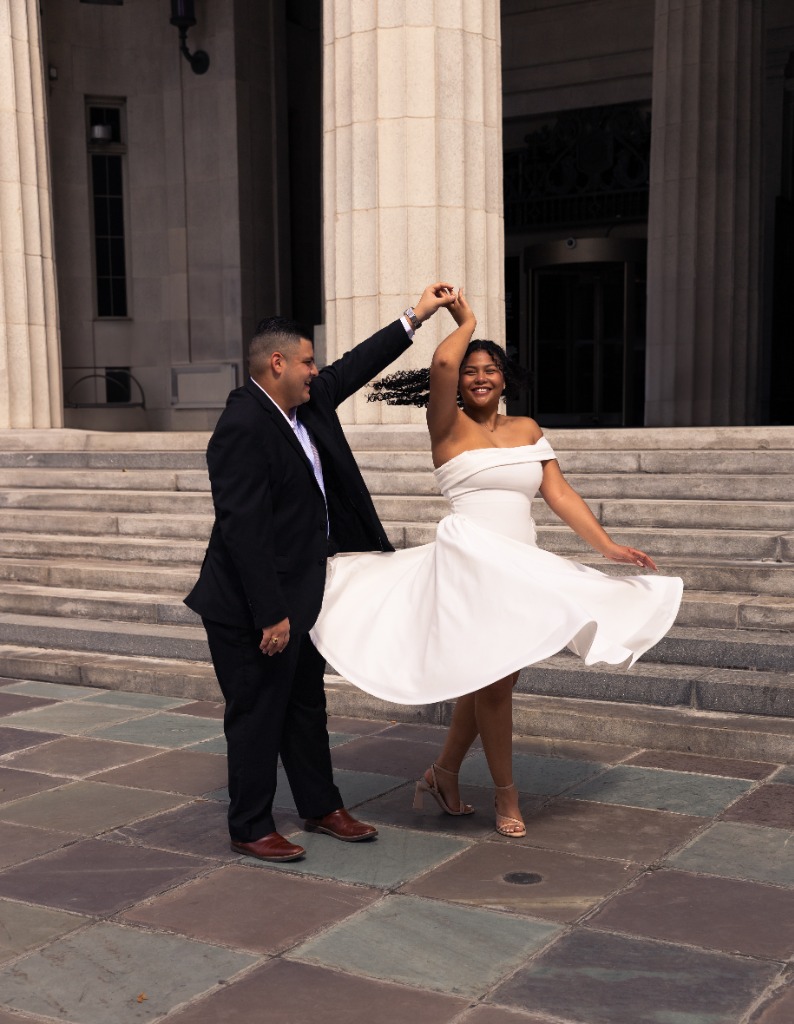 Couple dancing and spinning in front of classical stone columns