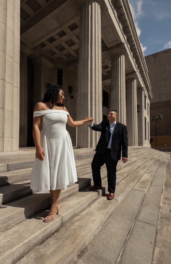 Couple holding hands and walking down classical building stairs