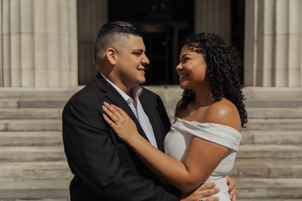 Close-up portrait of engagement couple smiling and looking lovingly at each other with building columns in the background