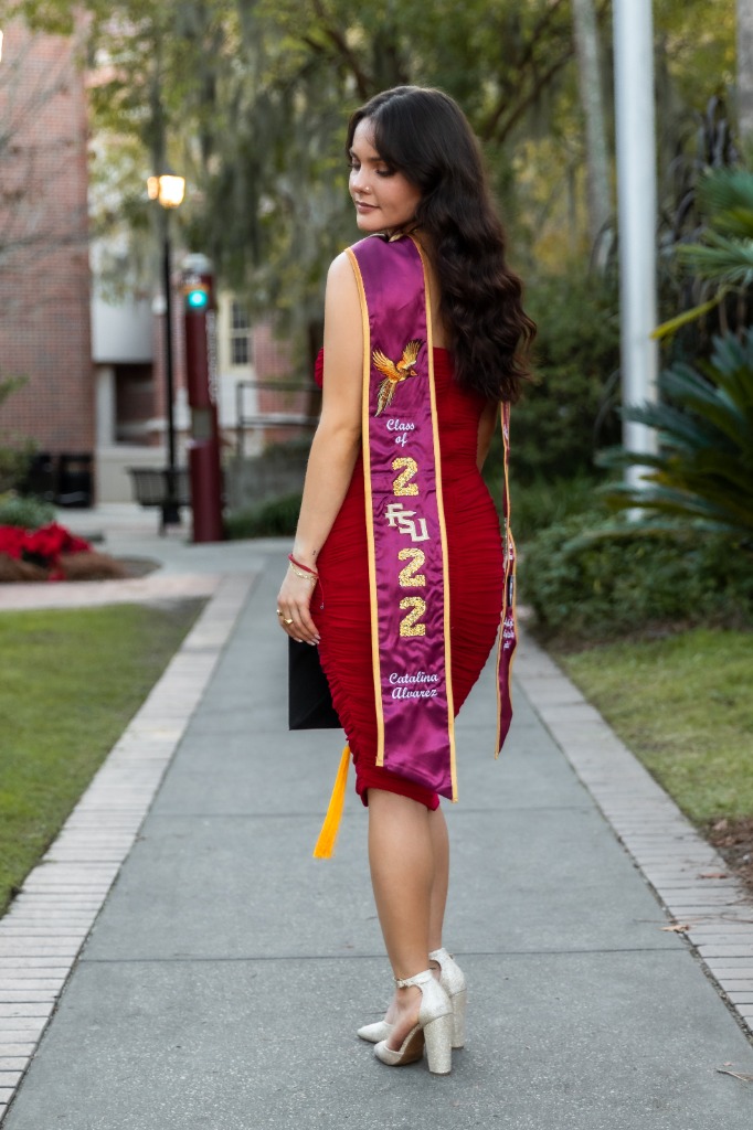 Graduate in red dress with FSU 2022 sash walking down walkway
