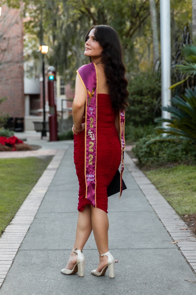 Graduate in red dress posing looking back with FSU 2022 sash