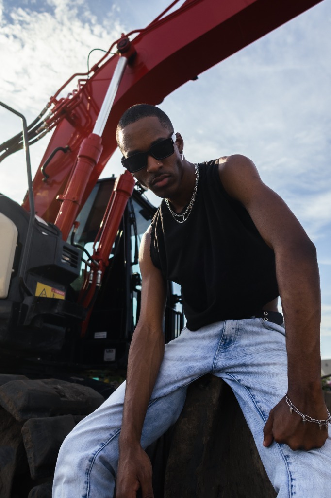 Man wearing sunglasses leaning on red industrial construction equipment
