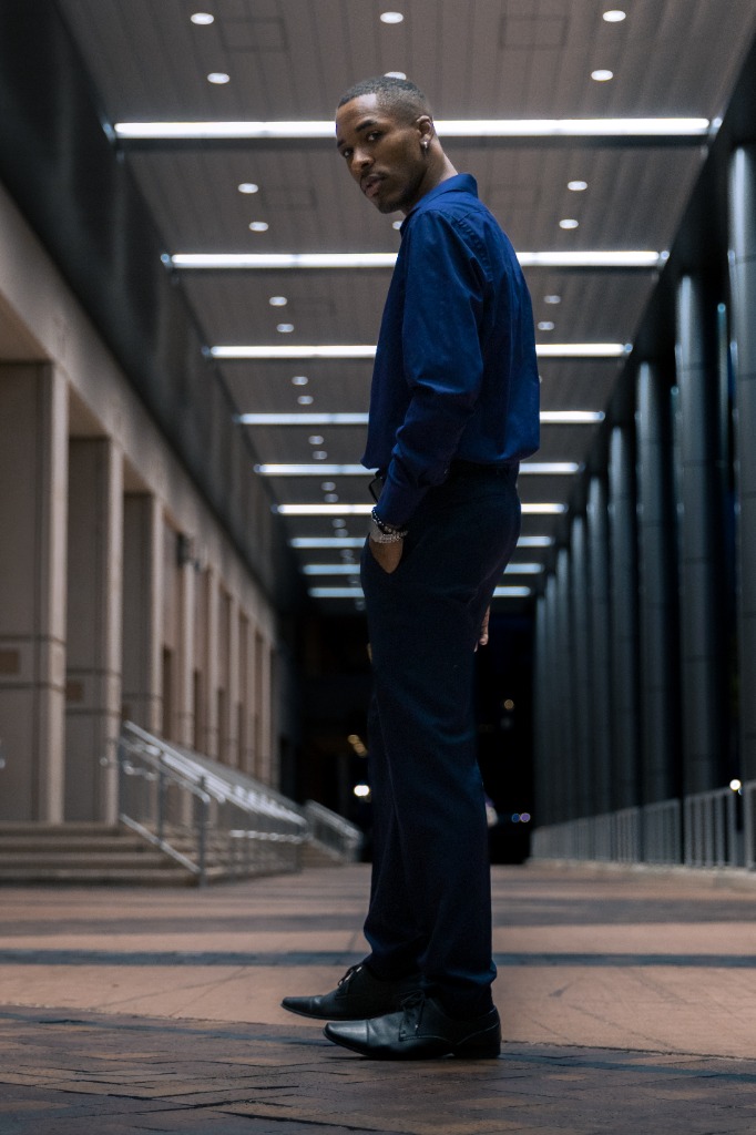 Man standing under architectural hallway lights looking back over his shoulder